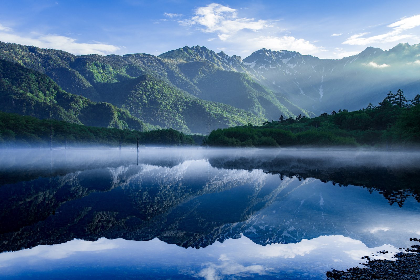 Taisho Pond's still water reflecting the surrounding peaks in the morning mist